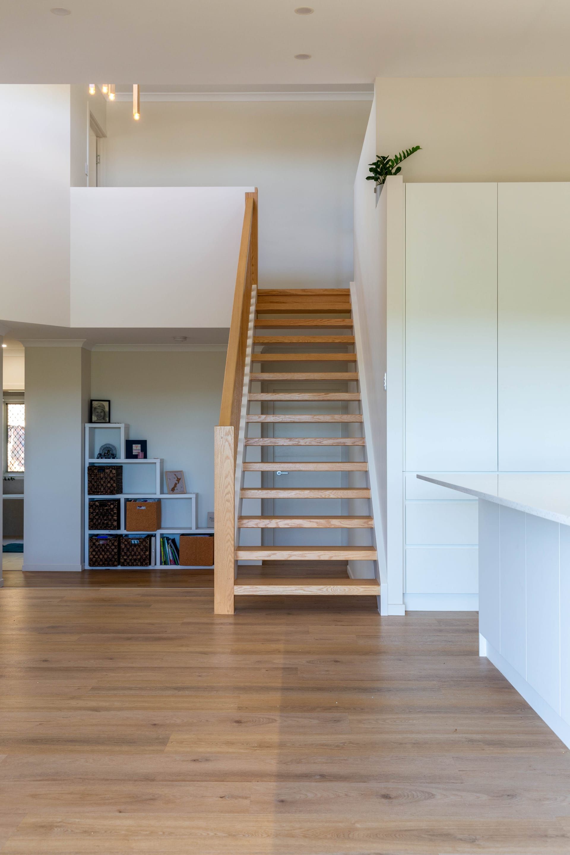 Timber staircase rising through a double-height void